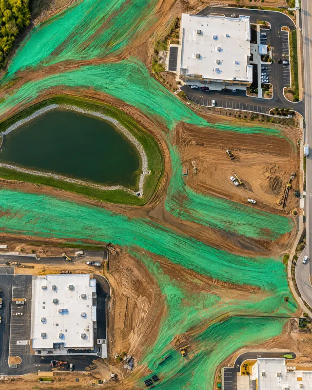 Aerial view of green hydroseed bands across a commercial development
